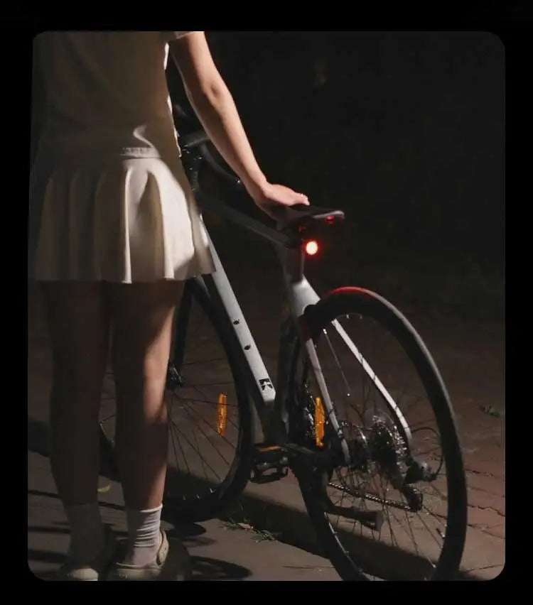 Black round bike light with red lens and hook mount