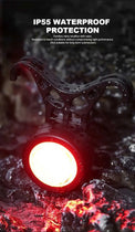 Black round bike light with red lens and hook mount