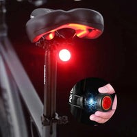 Black round bike light with red lens and hook mount