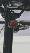 Black round bike light with red lens and hook mount