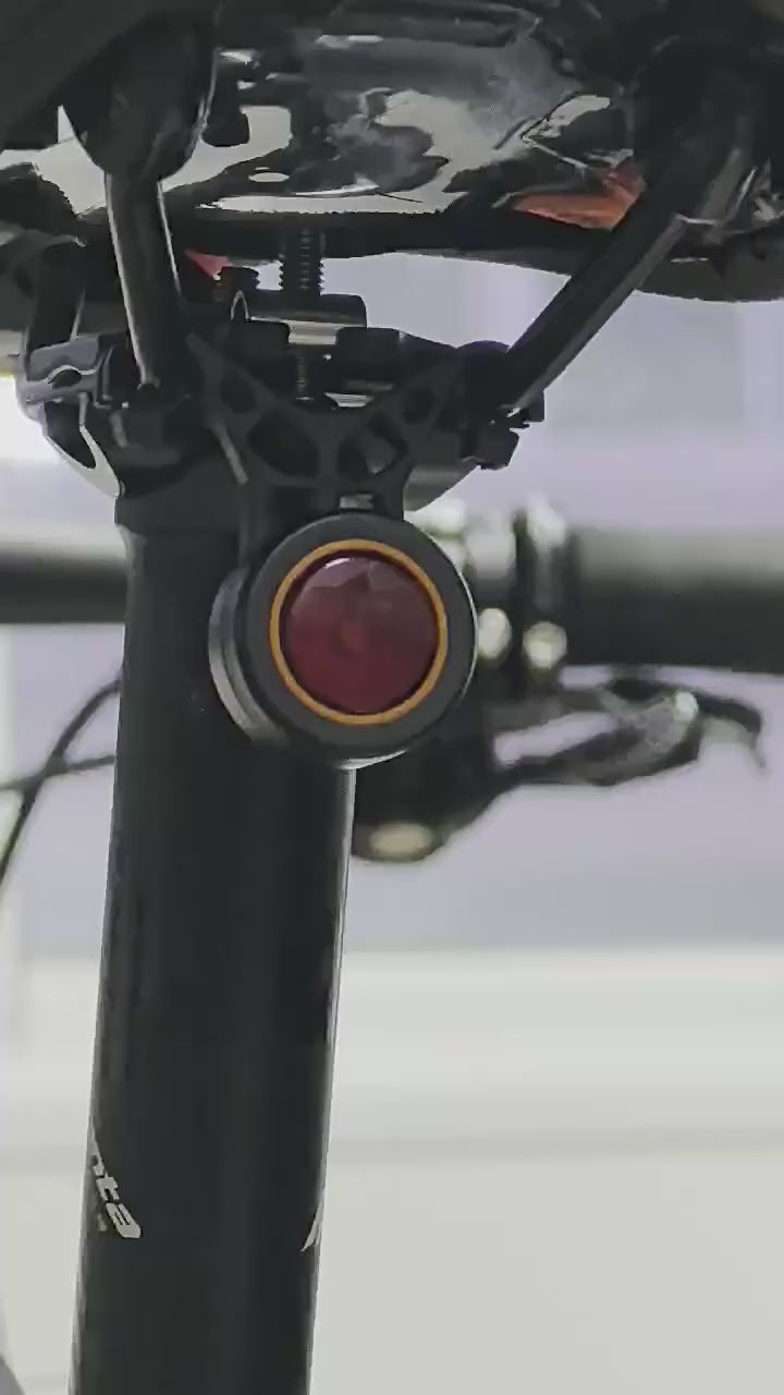 Black round bike light with red lens and hook mount
